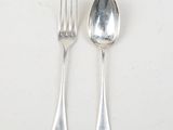 two silver spoons and a fork on a table