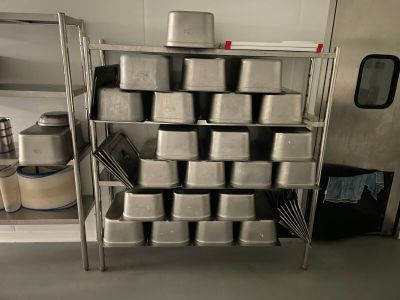 many pans stacked on a metal shelf in a kitchen