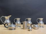 five silver pitchers sitting on a table with a black background