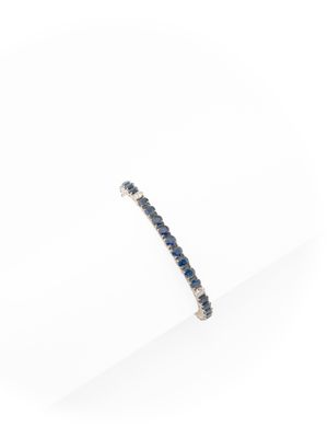 un gros plan d'un bracelet en saphir bleu et diamants posé sur une surface blanche