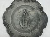 une assiette en argent sur laquelle est représentée une femme