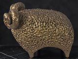 a gold statue of a sheep on a black surface