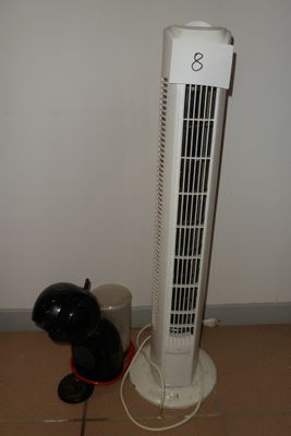 un ventilateur blanc posé par terre à côté d'un chien noir