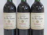 three bottles of red wine sitting next to each other on a white surface