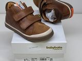 brown leather baby shoes with velcro straps on top of a white box