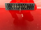 a red teddy bear sitting on top of a red car next to a ruler