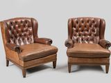 pair of leather armchairs with buttoned arms and footrests