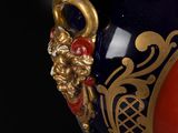 a blue vase with a red and gold decoration on it