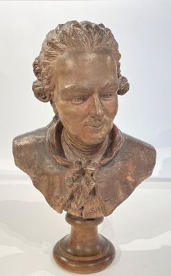 bronze bust of a man with a bow tie on top of a table