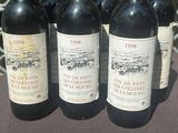 four bottles of red wine are lined up on a table