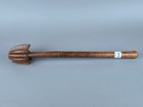 une vieille pipe en bois avec un manche en bois posée sur une surface grise