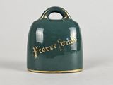 a green bell with gold lettering on it on a white surface