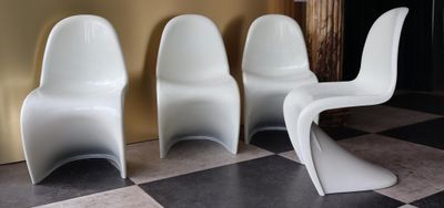 trois chaises en plastique blanc sont alignées sur un sol à carreaux