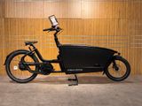 une photo d'un vélo électrique noir garé devant un mur en bois