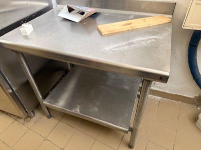 une table de travail en acier inoxydable sur laquelle est posée une planche à découper