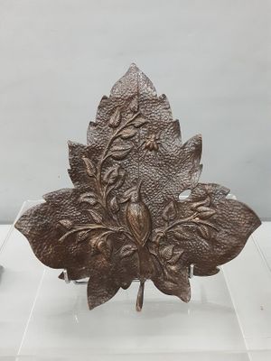 sculpture of a leaf on a clear base on a white surface