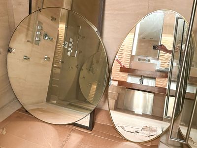 a bathroom with a large round mirror and a walk in shower