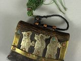 a small metal purse with a green string on top of it