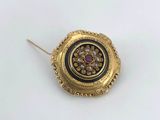 a close up of a gold and black broochle on a white surface