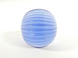 une boule de verre bleue posée sur une surface blanche