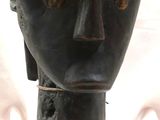 une sculpture noire représentant la tête d'un homme, posée sur une table
