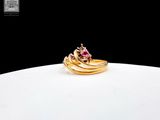 une bague en or sertie d'une pierre rose, posée sur une assiette blanche