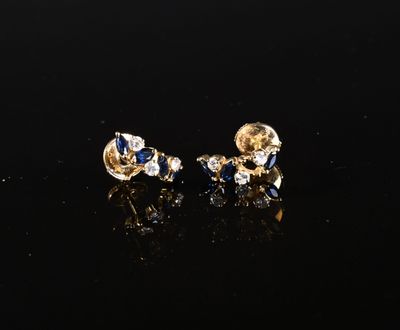 une paire de boucles d'oreilles en or et saphir posées sur un fond noir