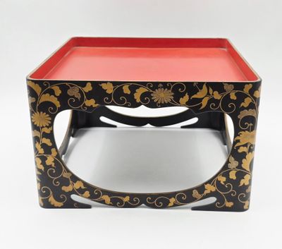 une table noire et dorée sur laquelle est posé un plateau rouge