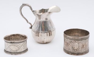 three pieces of silverware including a pitcher, cup, and saucer