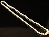 a close up of a pearl necklace on a black surface