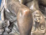 a bronze statue of a woman sitting on a rock