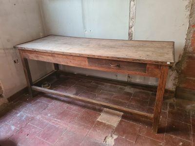 a wooden table with a drawer on it in the corner of a room