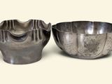 two metal bowls sitting next to each other on a white surface