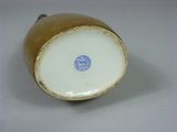 a brown and white vase with a blue label on it