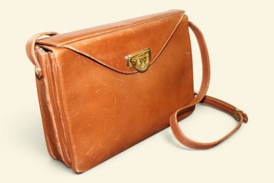 brown leather handbag on a white background with a brown strap
