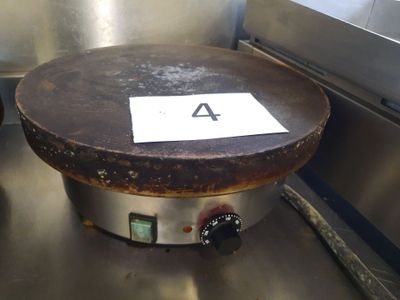 une vieille poêle sur laquelle est accrochée une pancarte, posée sur une table