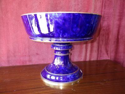a purple bowl on a wooden table with a red curtain in the background