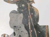 a metal sculpture of a man with a hat and a teddy bear