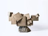 a sculpture made out of cardboard blocks sitting on top of a rock