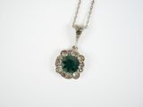 a close up of a necklace with a green stone on it