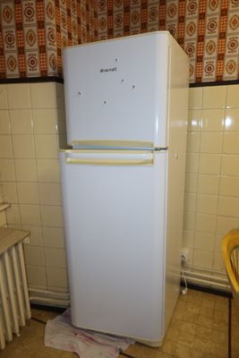 a white refrigerator sitting in a kitchen next to a yellow chair