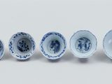 six blue and white porcelain bowls are lined up on a white surface