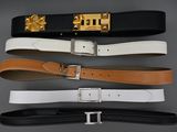 trois ceintures ornées de boucles dorées sur fond gris