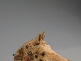 une image représentant une tête de cheval en bois sur fond gris