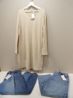 two pairs of jeans and a sweater on a hanger in front of a white wall