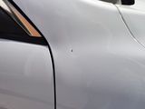a close up of a white car with a dent in it