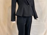a mannequin wearing a black suit and tie on a stand