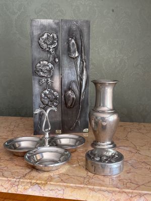 un vase en argent et deux plats en argent posés sur une table