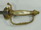 a gold sword with a black handle on a white surface