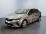 La voiture argentée est garée dans une grande pièce au sol noir.